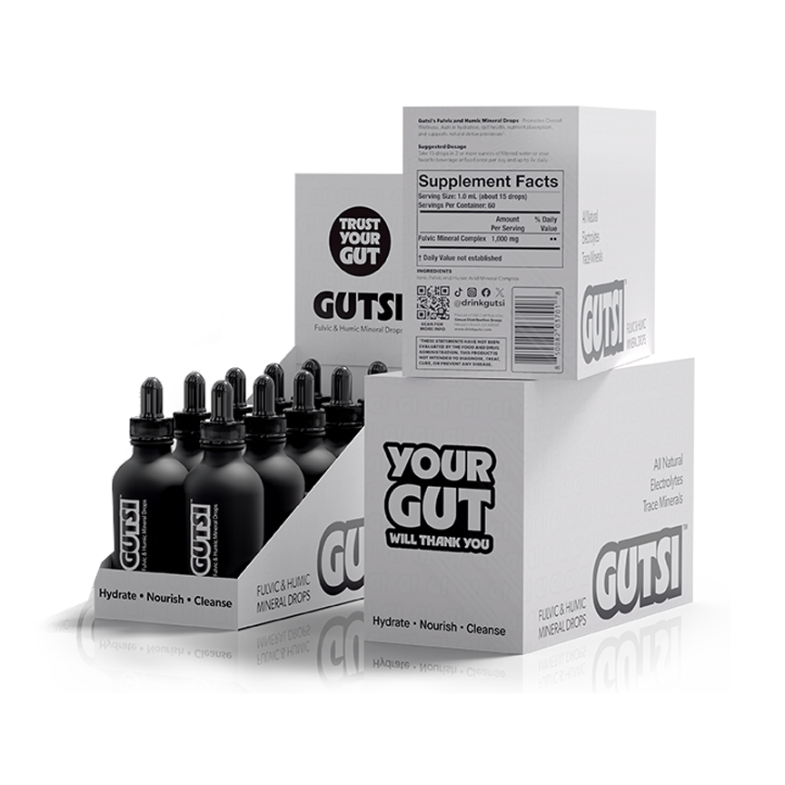 GUTSI Fulvic and Mineral Hydration Drops supplement bottles and packaging boxes on a clean white background. The display shows multiple black dropper bottles in a clear-front cardboard tray, with white boxes behind them featuring bold black GUTSI branding and supplement facts panel.