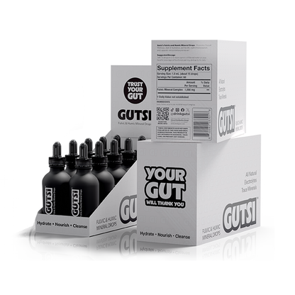 GUTSI Fulvic and Mineral Hydration Drops supplement bottles and packaging boxes on a clean white background. The display shows multiple black dropper bottles in a clear-front cardboard tray, with white boxes behind them featuring bold black GUTSI branding and supplement facts panel.